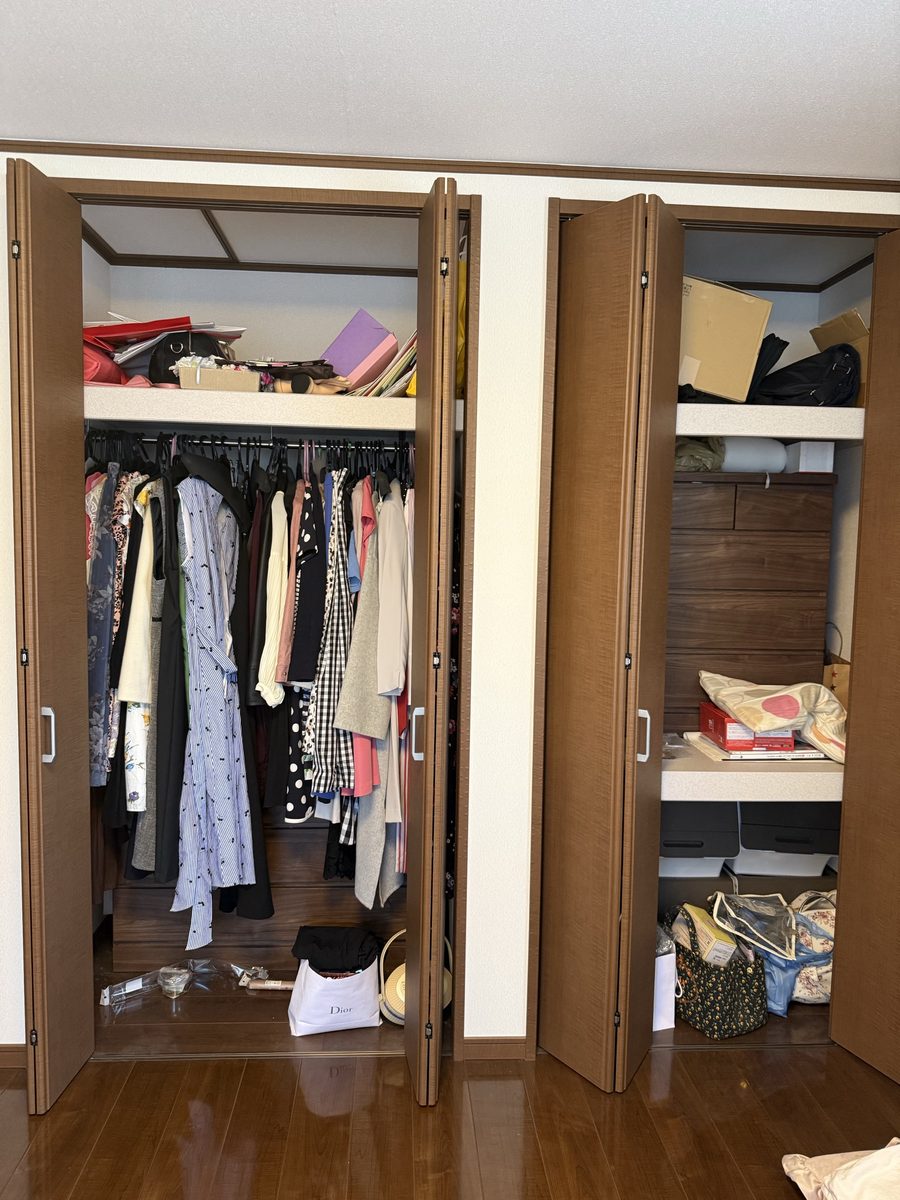 片付ける前のクローゼット。服が詰まり、床や棚の上にバッグや袋が置かれている